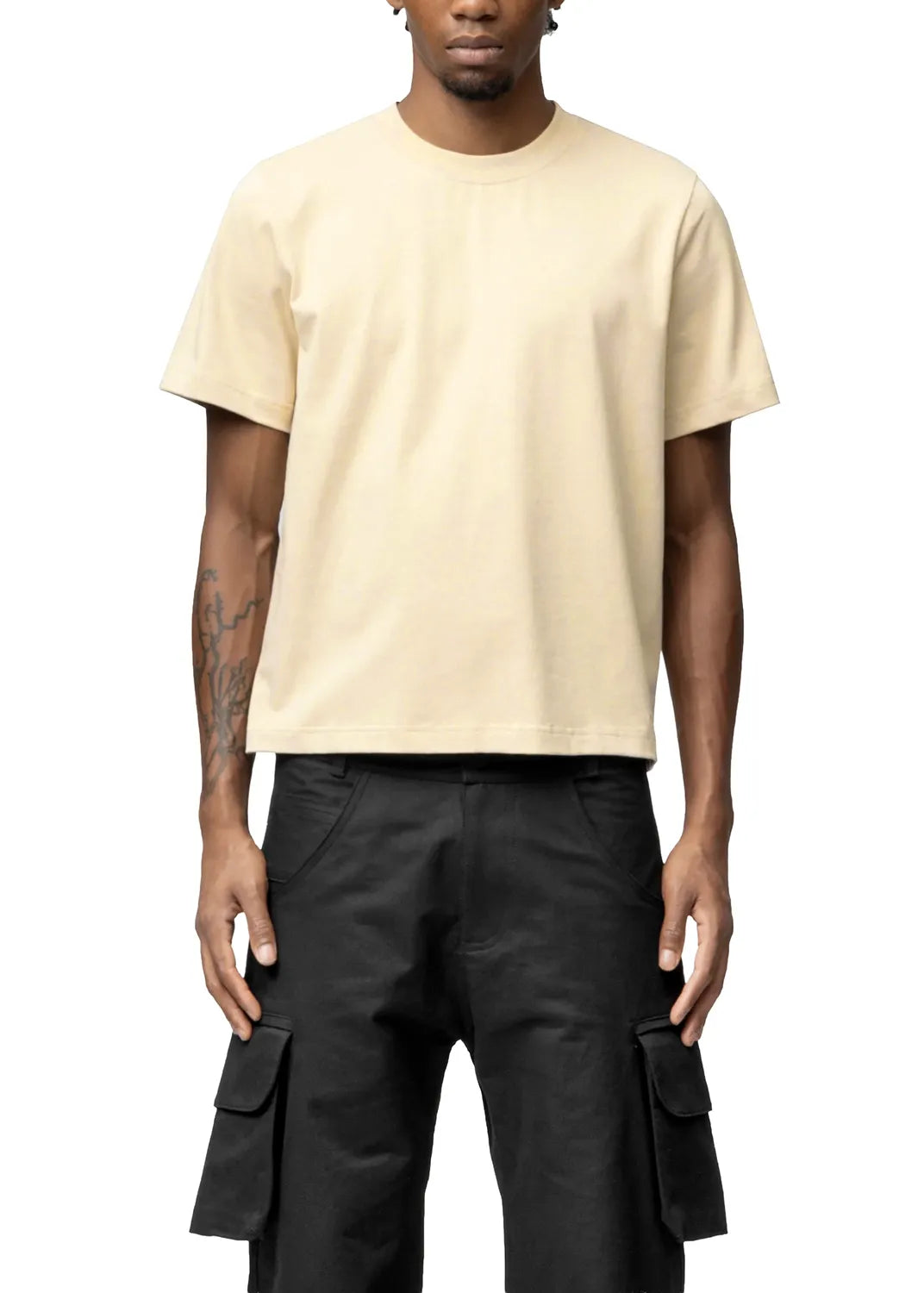 Person wearing a beige t-shirt and black cargo pants on a white background