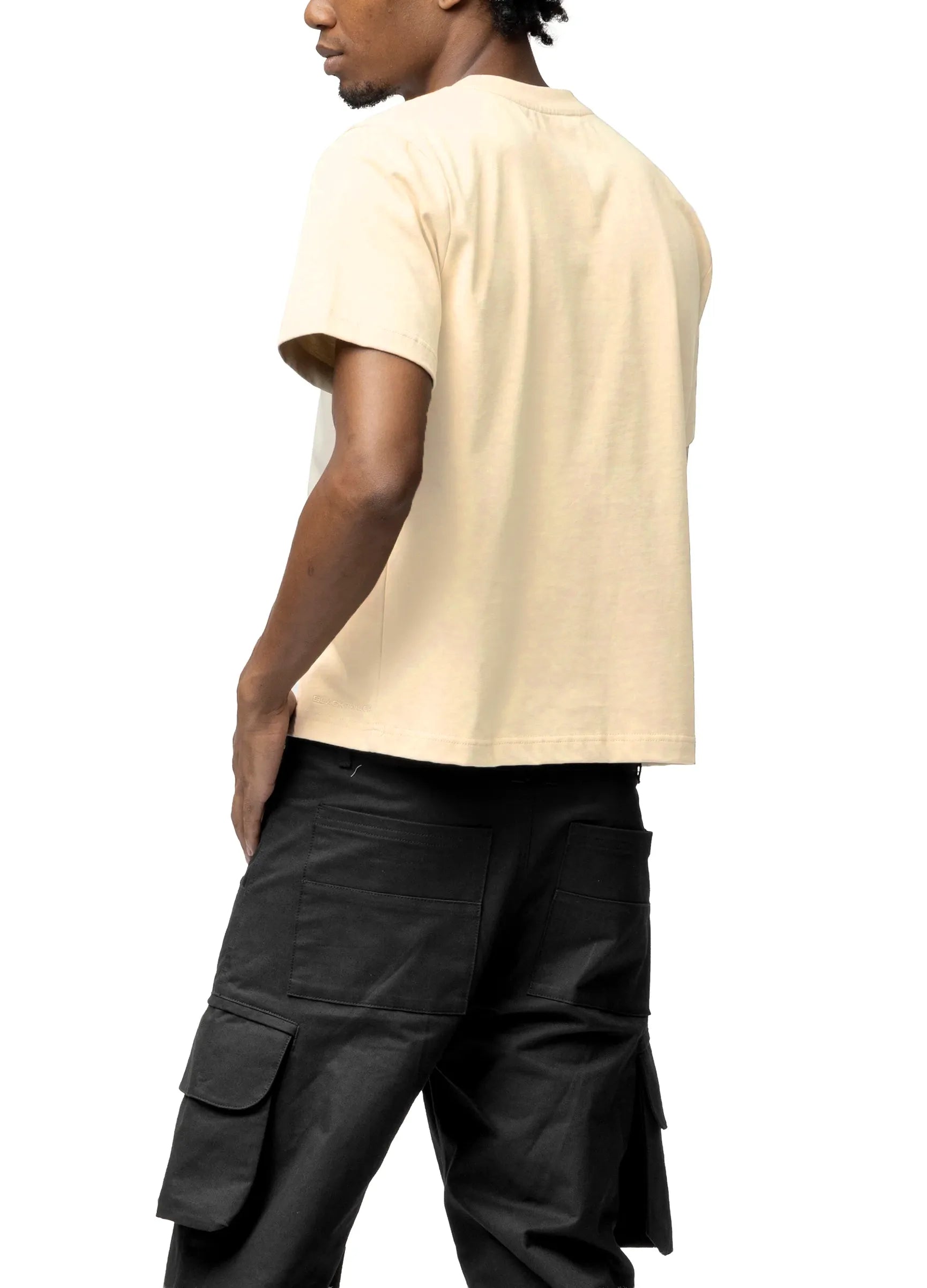 Person wearing a beige t-shirt and black cargo pants on a white background