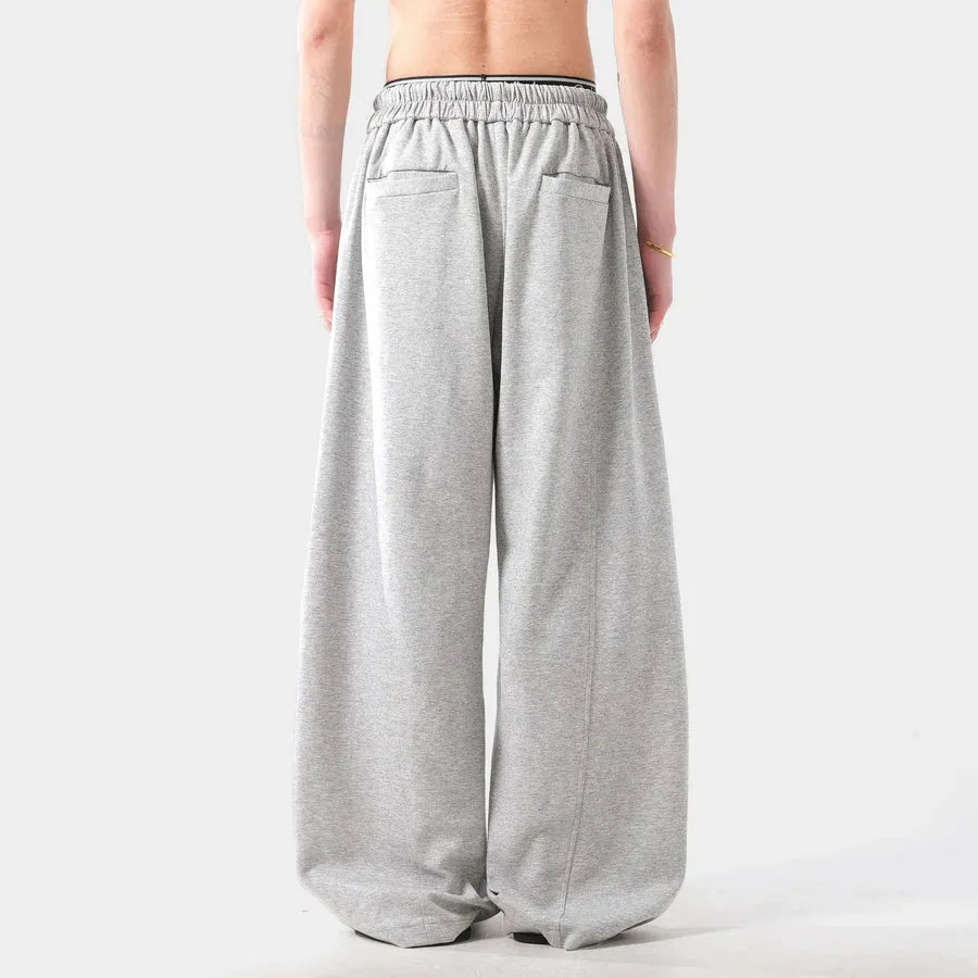 Person wearing grey wide-leg pants on a white background