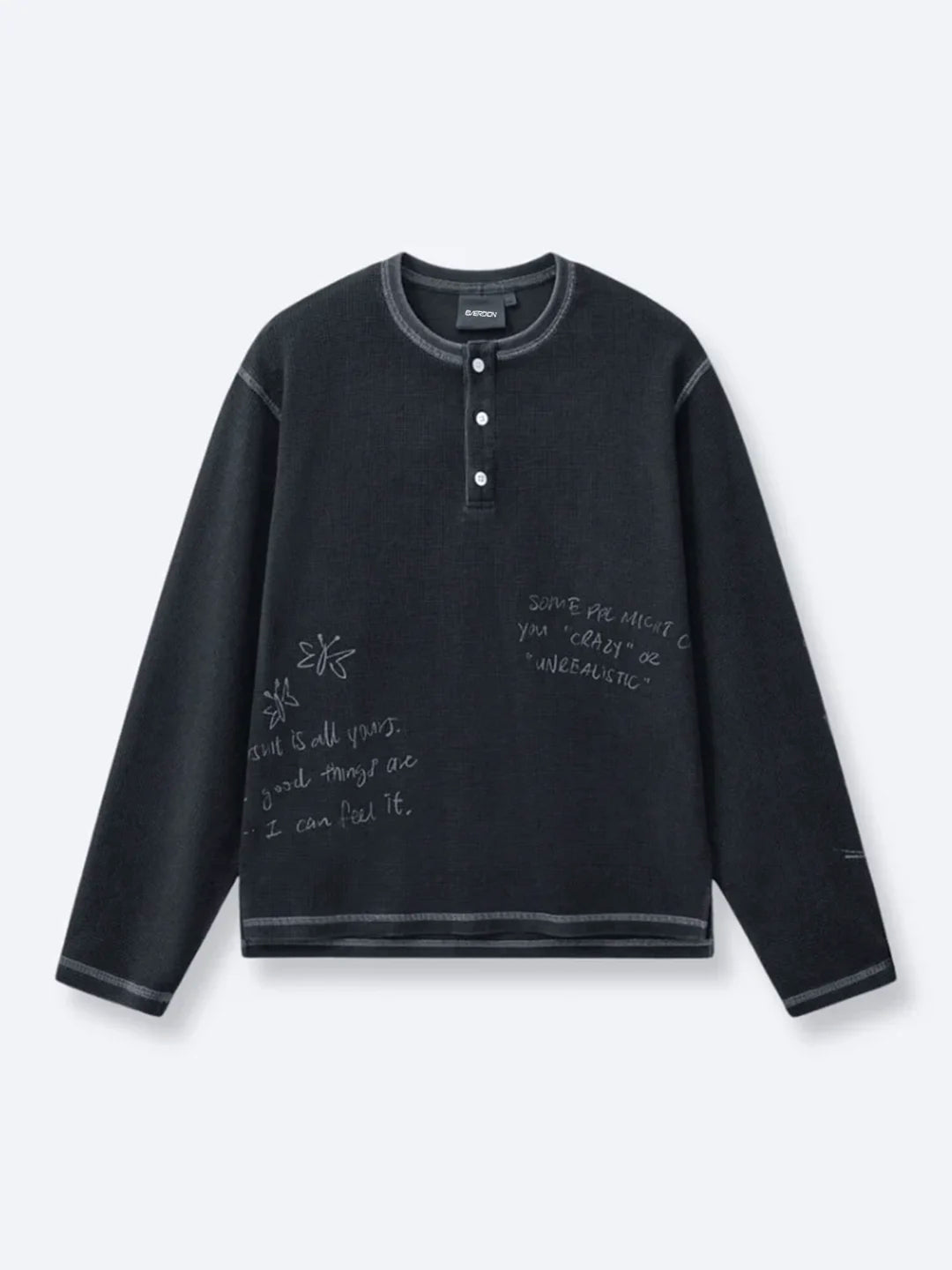A dark charcoal grey long-sleeve henley shirt with white handwritten-style text and doodle graphics printed on the front