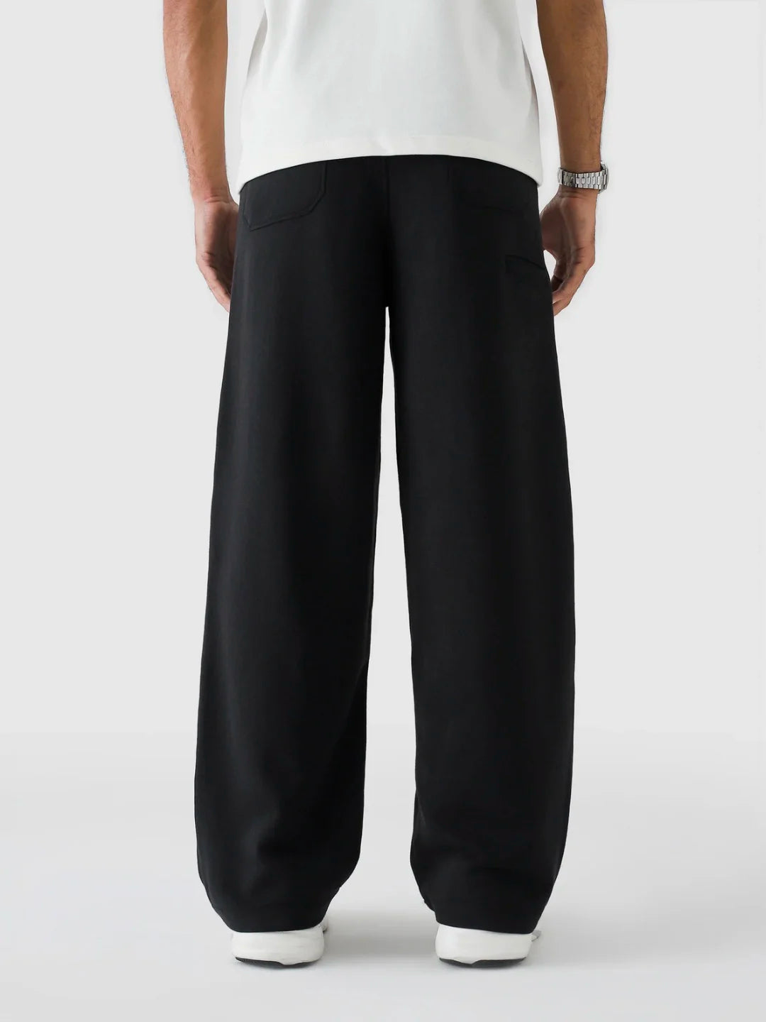 Person wearing black pants and a white shirt on a light grey background