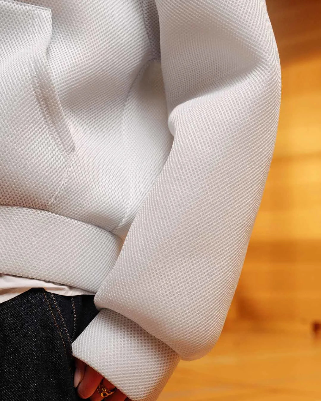 Close-up of a textured white fabric sleeve on a wooden surface