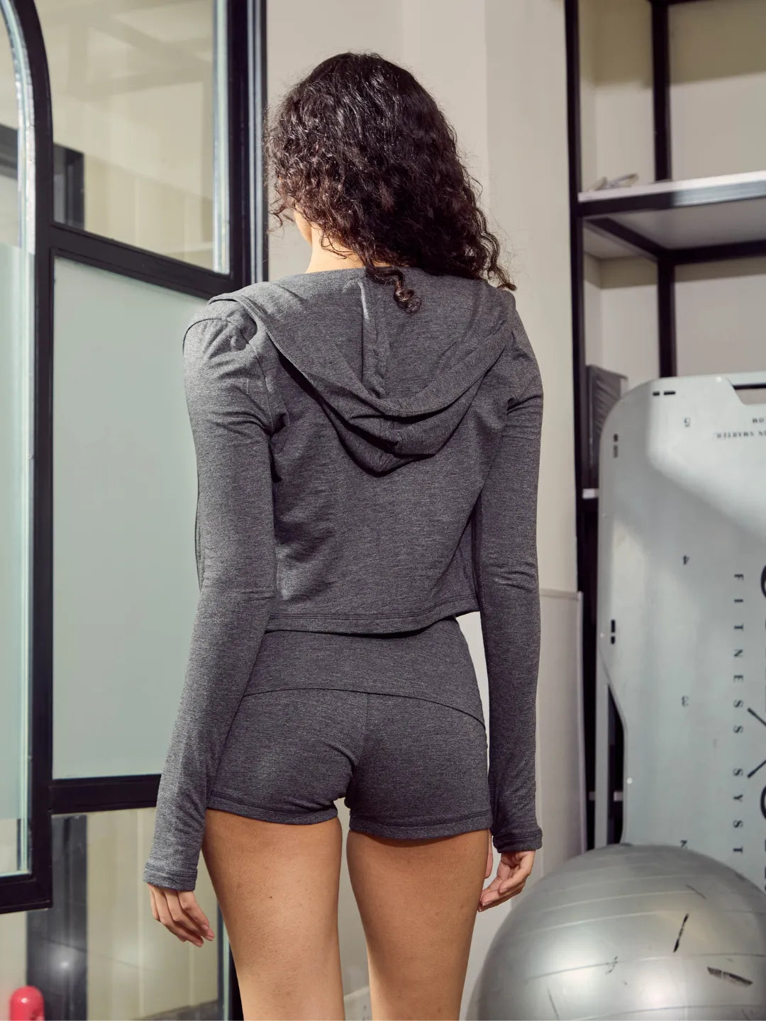 Person wearing a grey hoodie and shorts in a gym setting