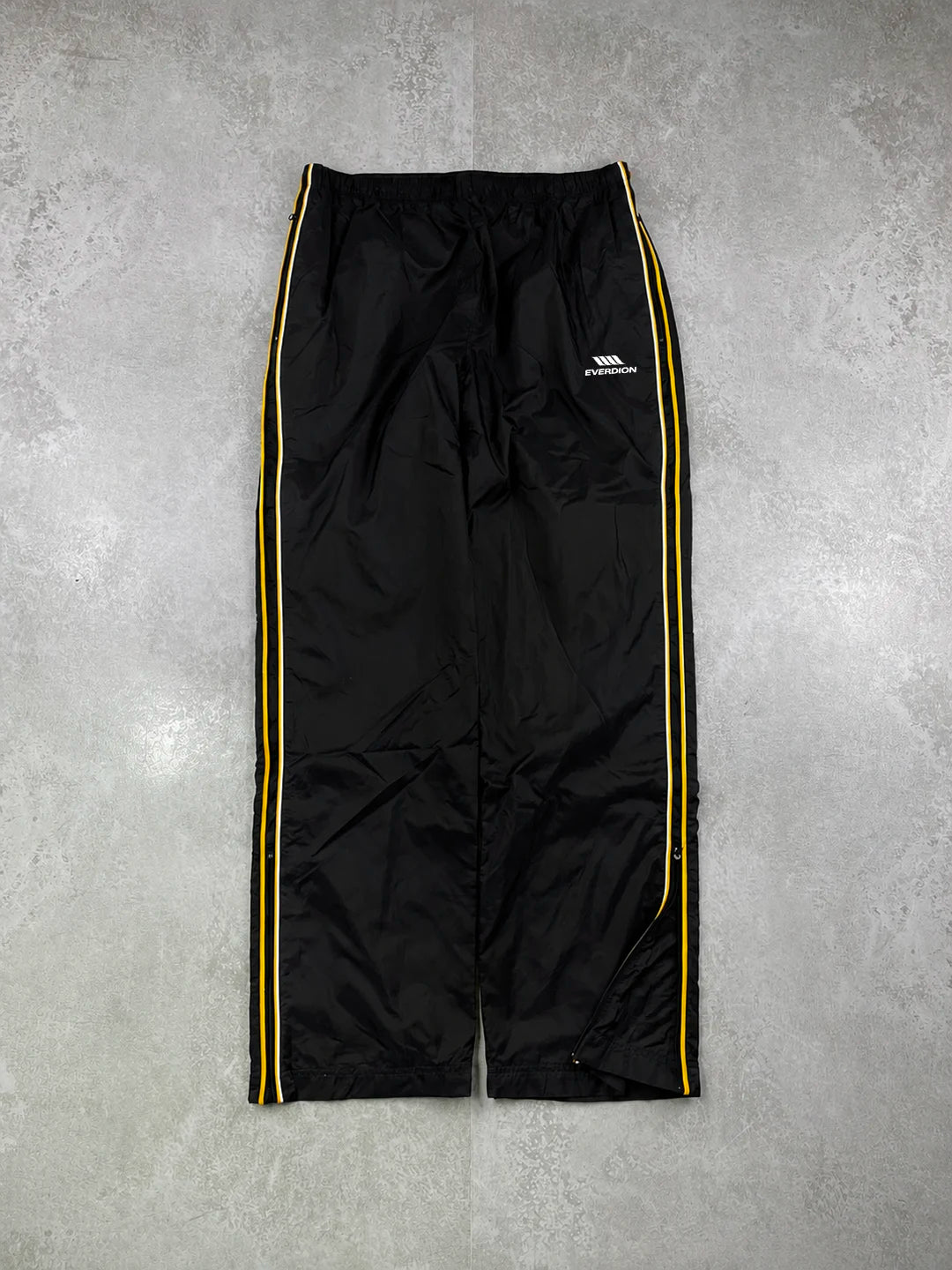 Black track pants with a red stripe and brand logo on a grey background