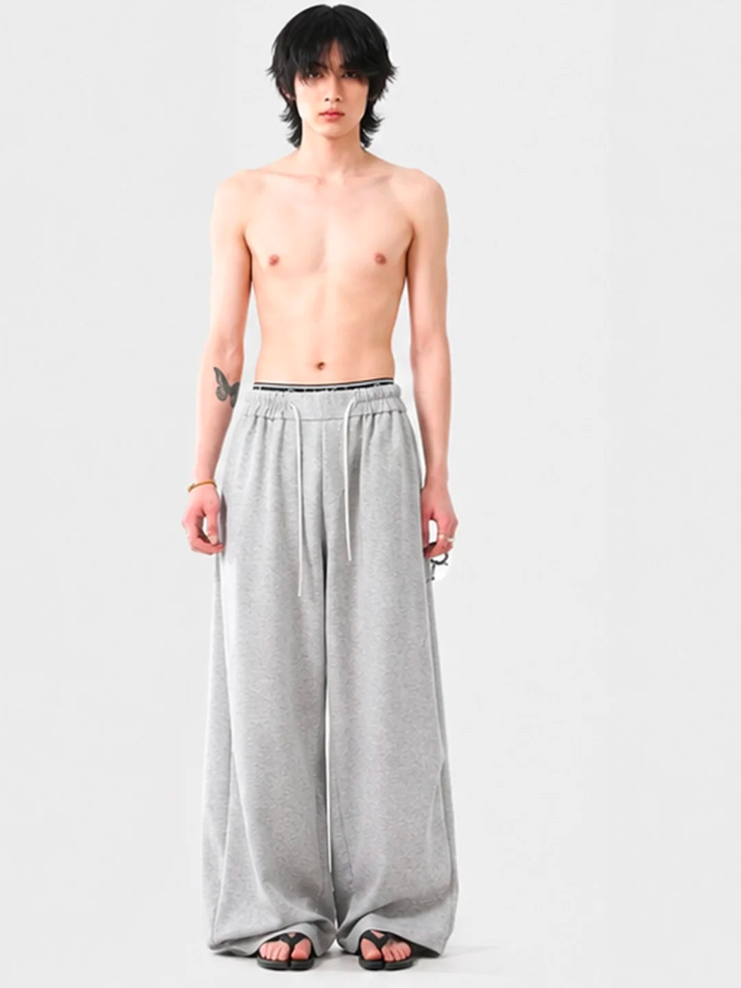 Person wearing grey wide-leg sweatpants on a white background