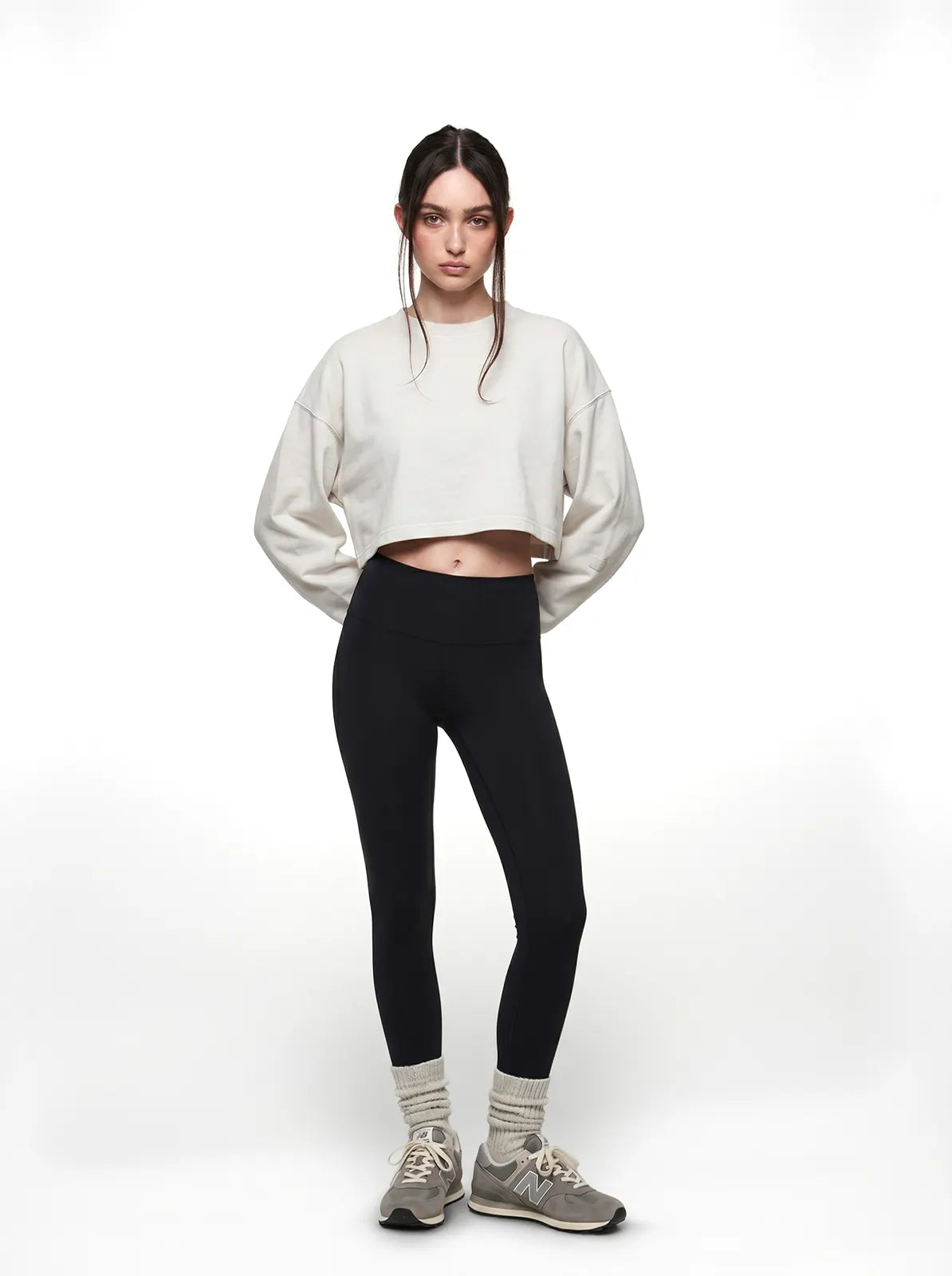 Person wearing a white cropped t-shirt and black leggings on a white background