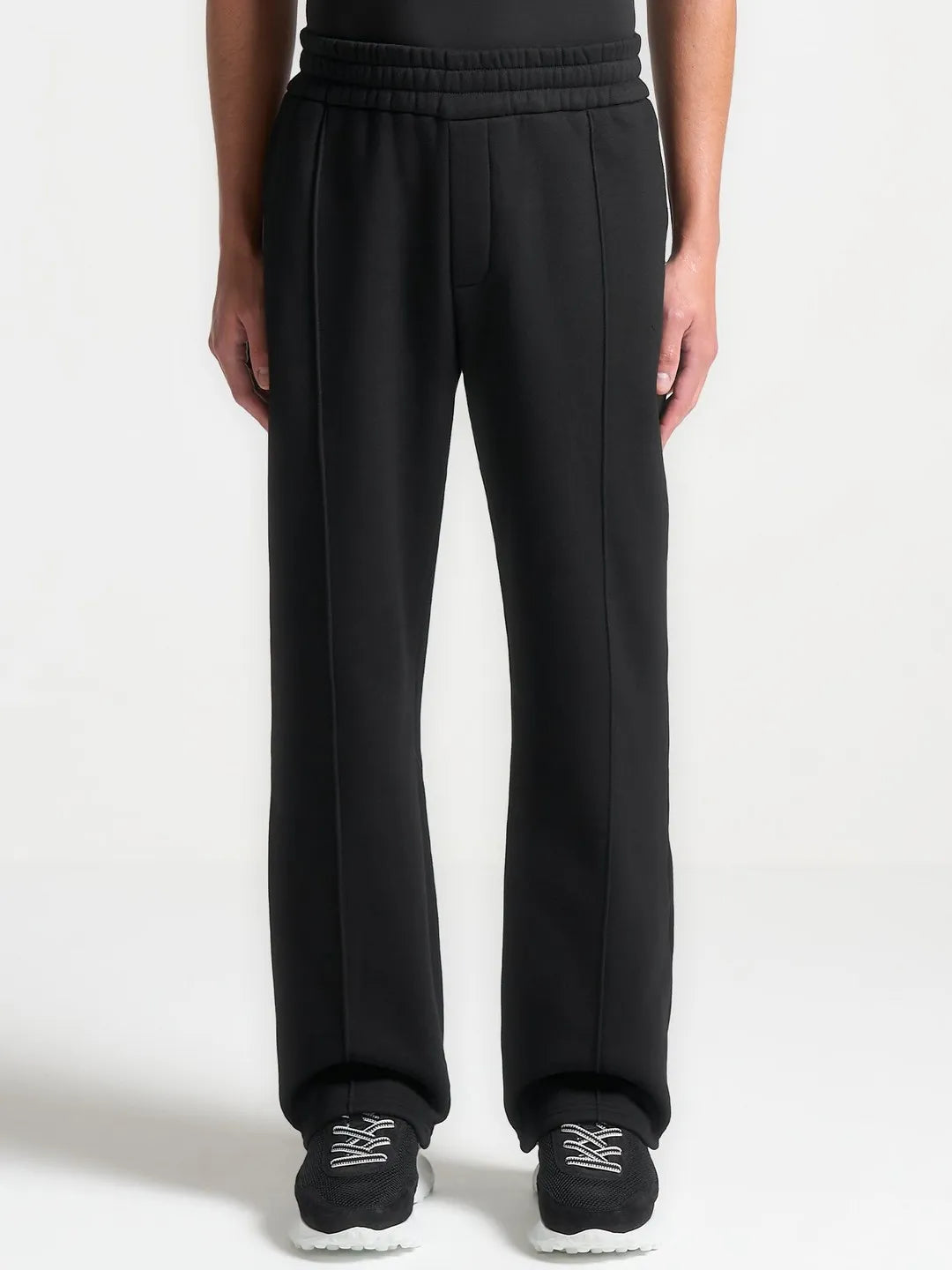 Black sweatpants worn by a person on a white background