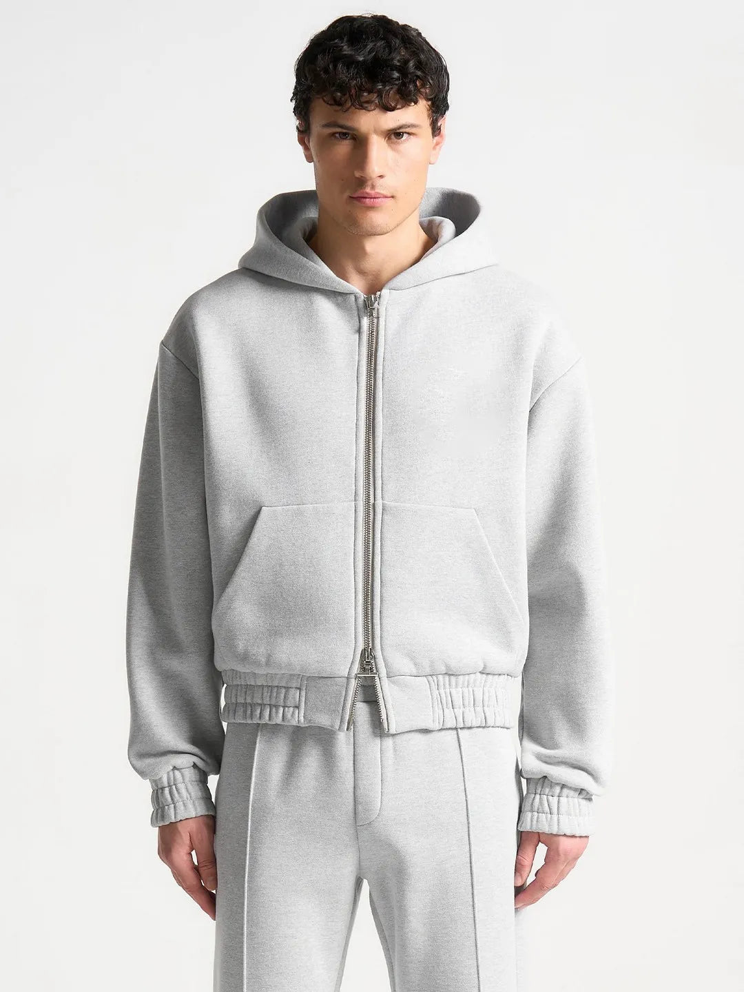 Man wearing a gray tracksuit on a white background