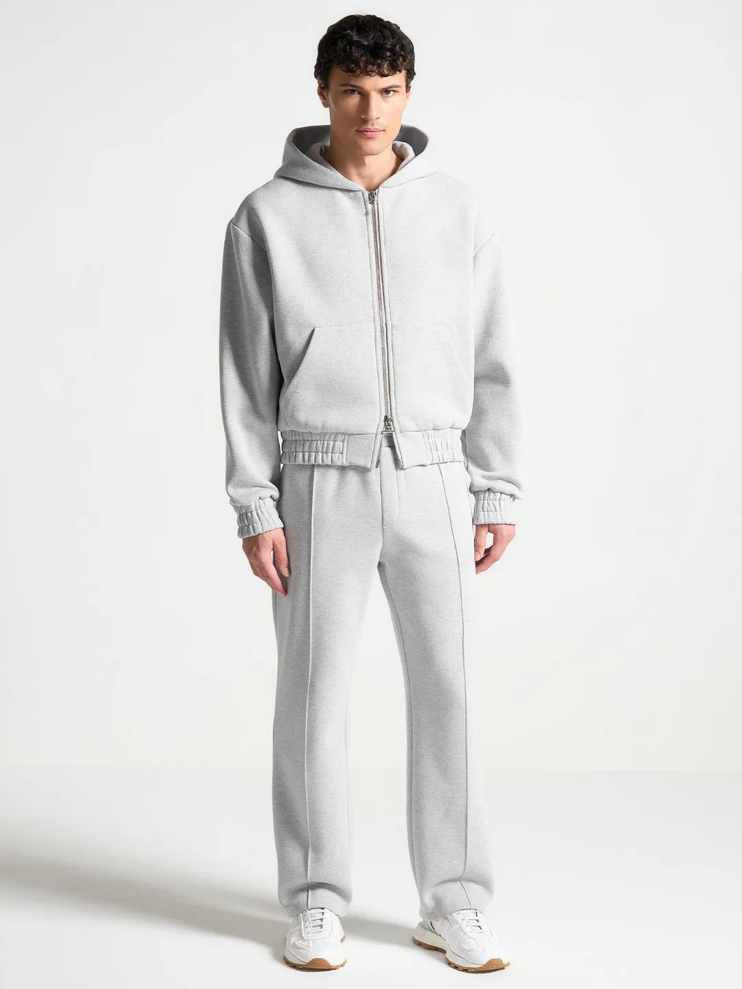 Person wearing a gray tracksuit on a white background