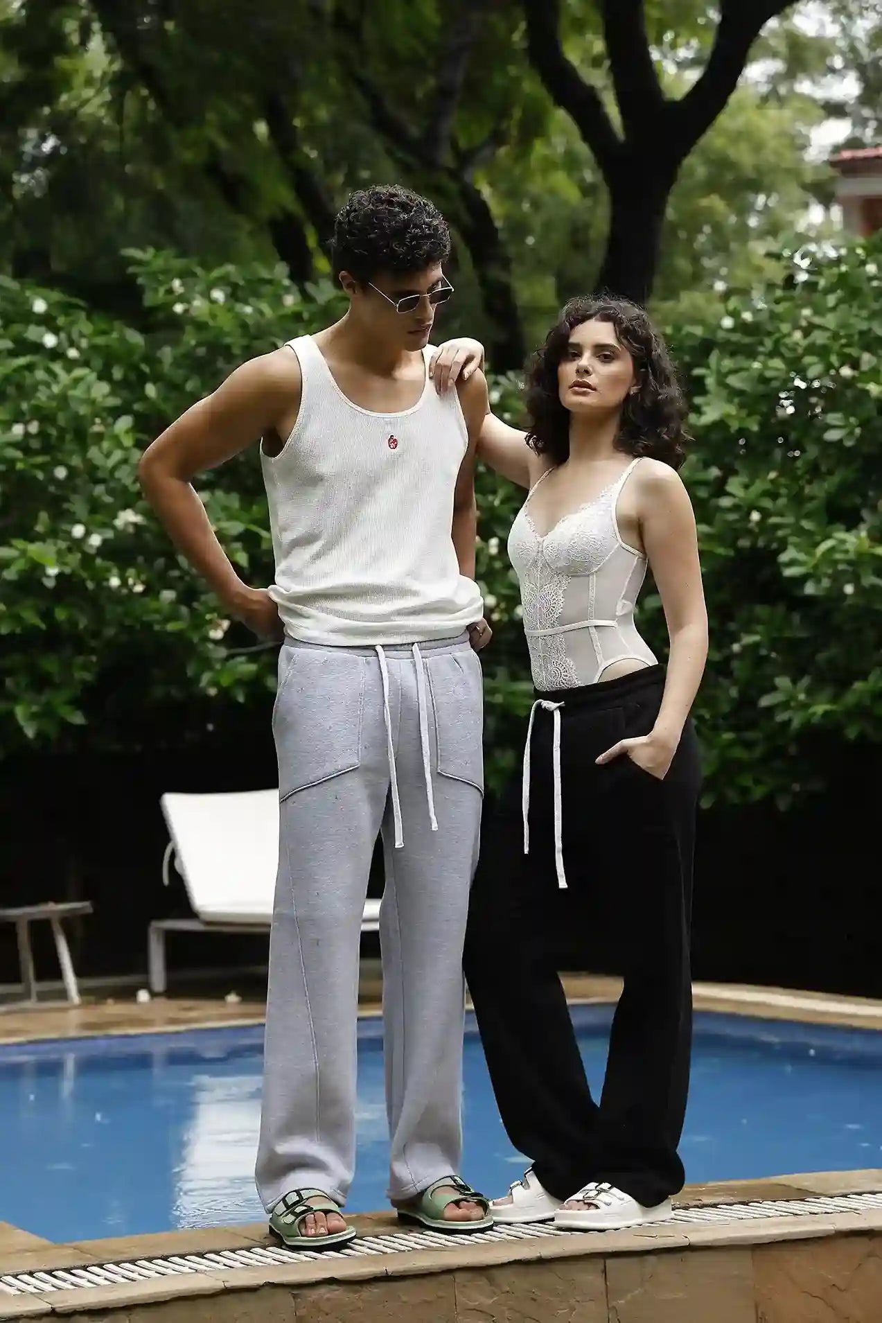 Two people standing by a pool with trees in the background