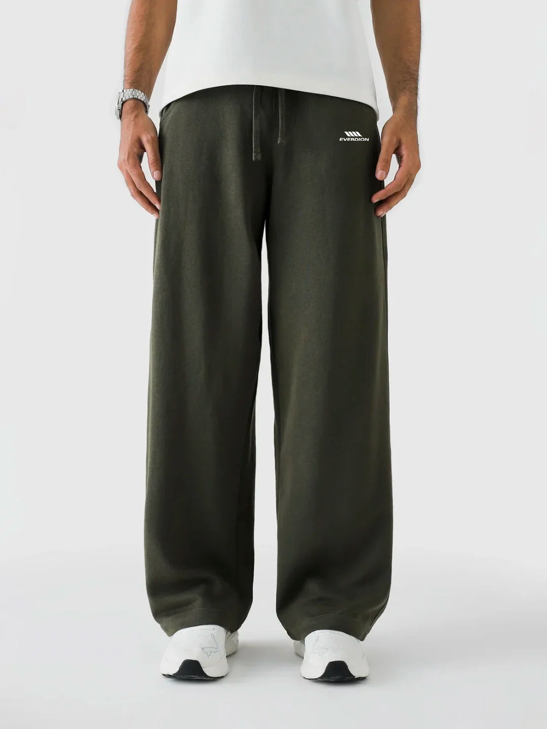 Person wearing olive green wide-leg pants with a white logo on a white background