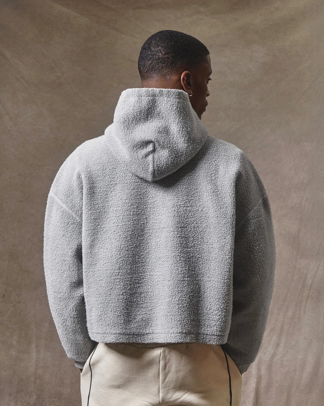Person wearing a gray fleece jacket against a beige background