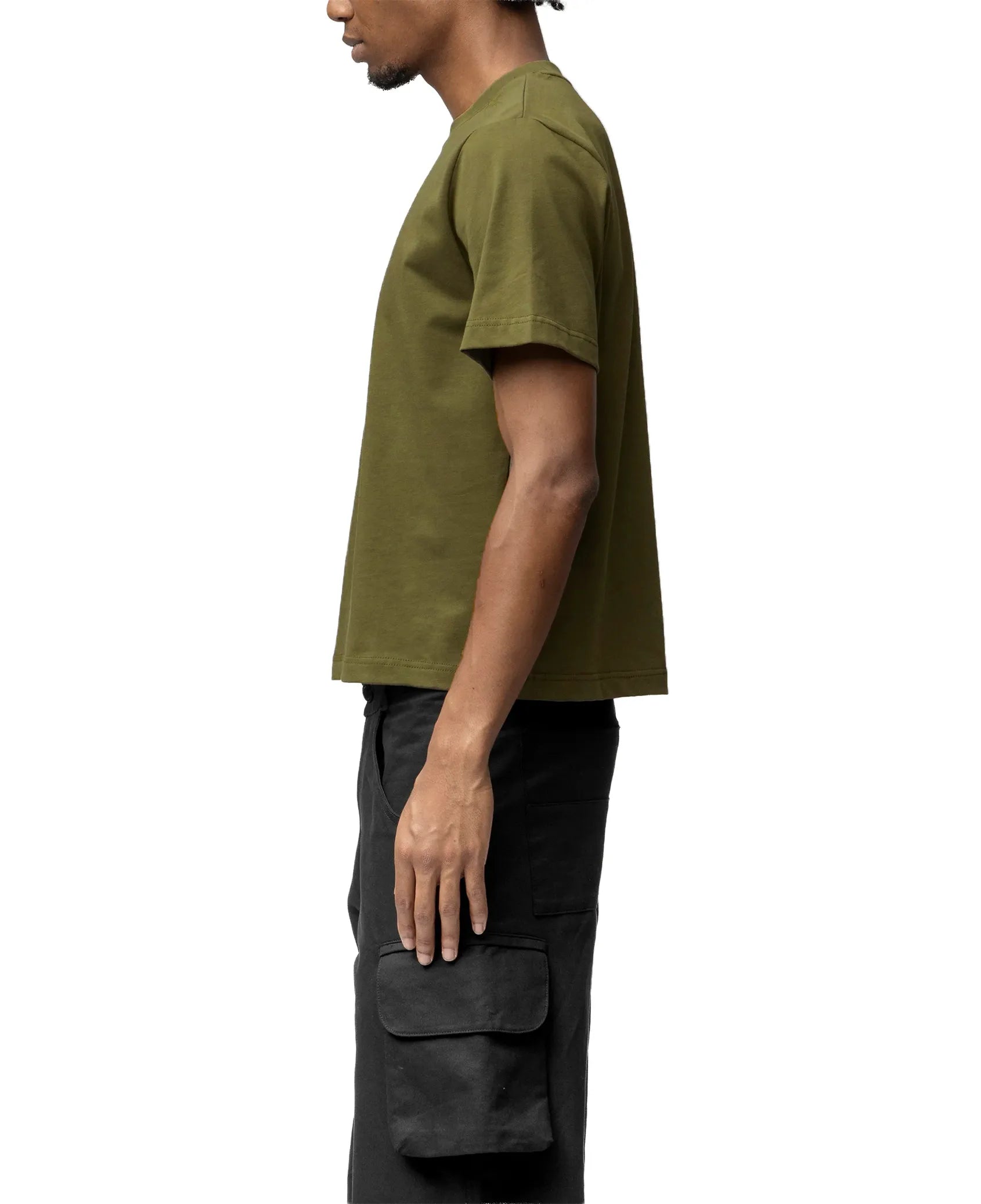 Person wearing an olive green t-shirt and black cargo pants on a white background