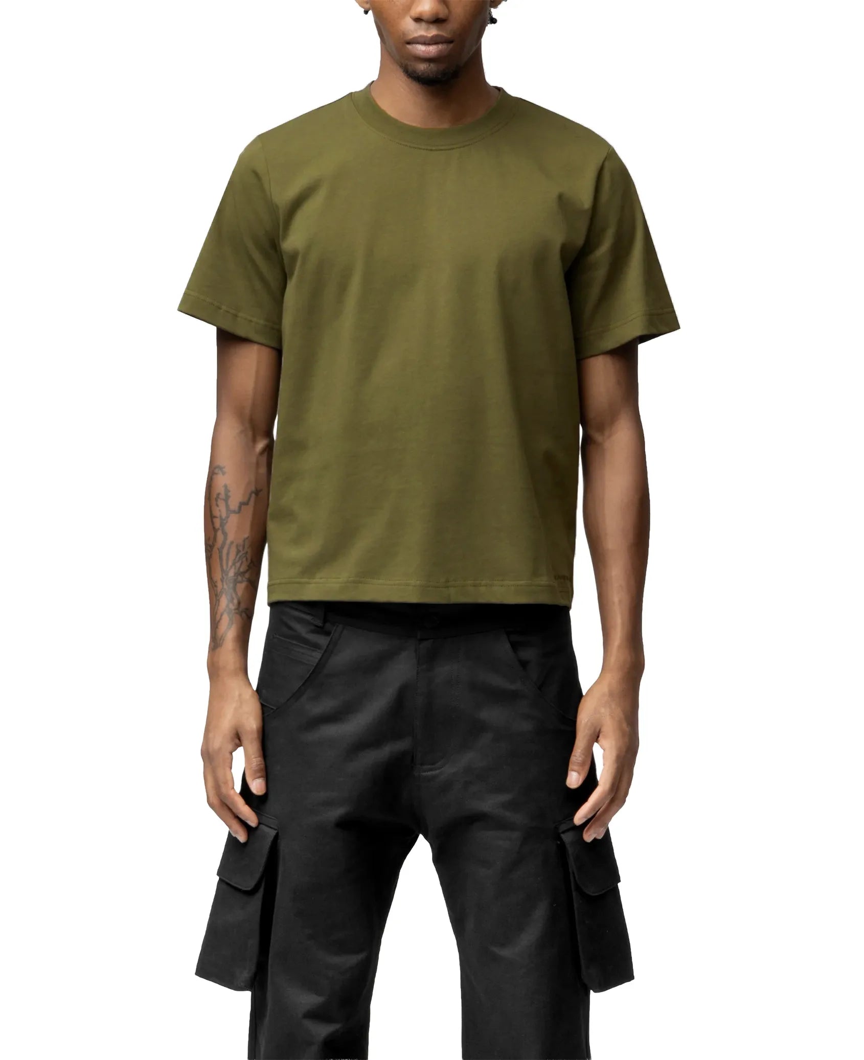 Person wearing an olive green t-shirt and black pants on a white background
