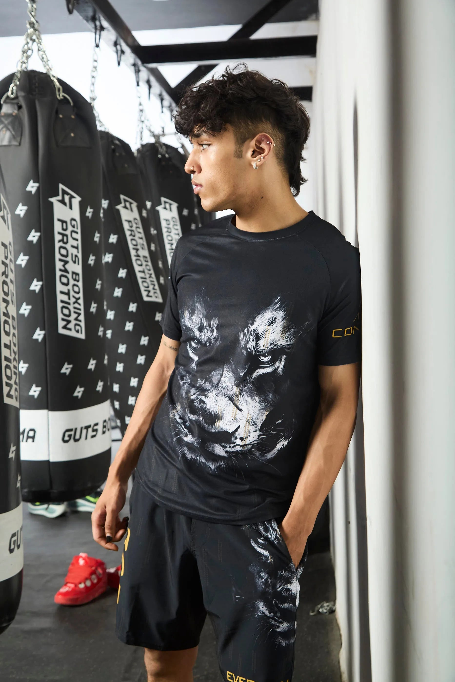 Person wearing a t-shirt and shorts with a wolf graphic in a gym setting