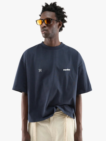 Person wearing a navy blue t-shirt with white text and graphics, standing against a plain background.