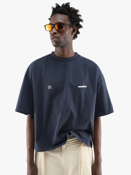 Person wearing a navy blue t-shirt with white text and graphics, standing against a plain background.