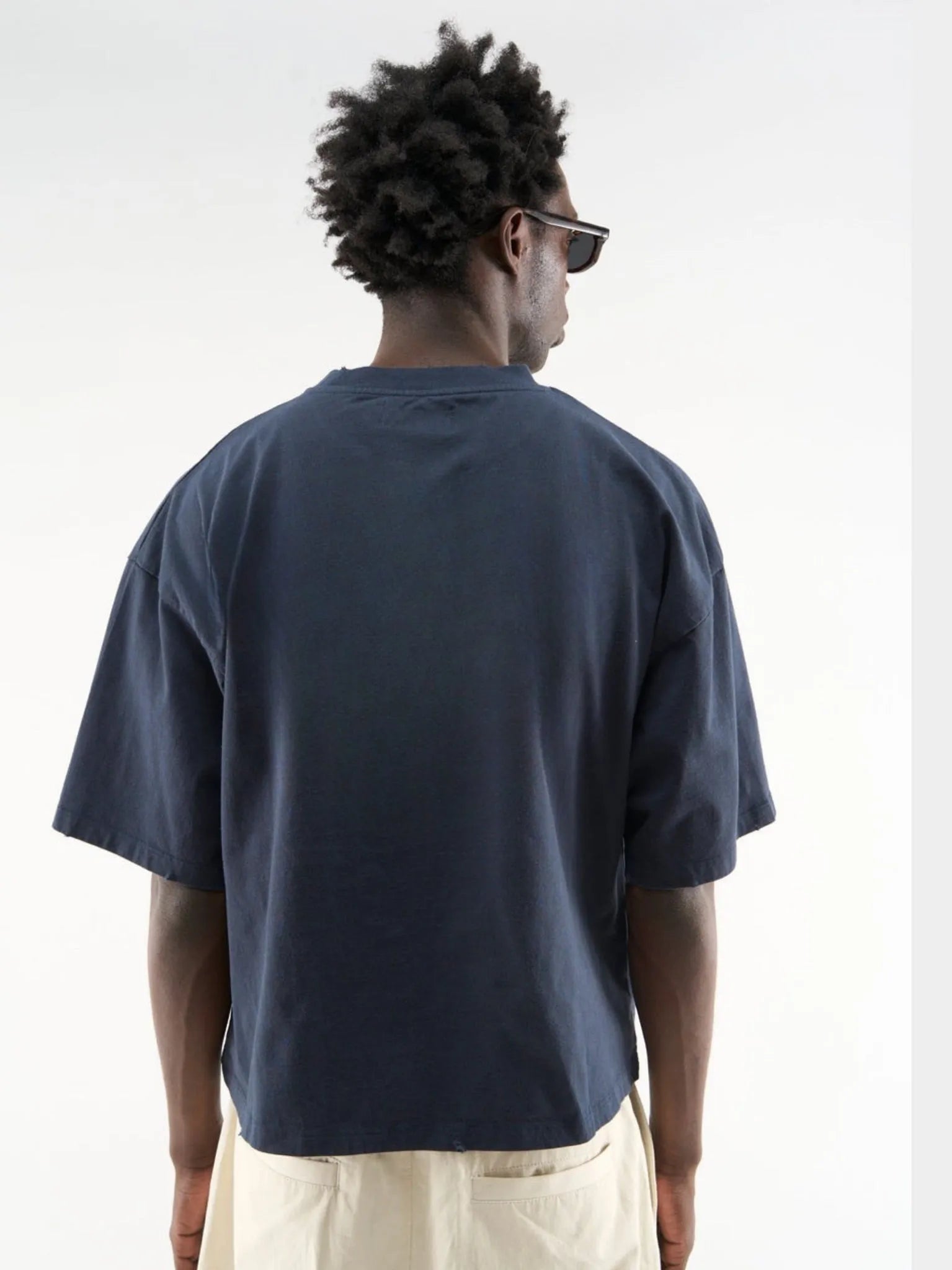 Person wearing a navy blue t-shirt and beige pants on a white background