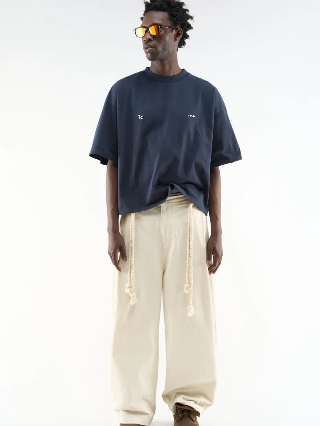 Man wearing a navy t-shirt and beige pants on a white background