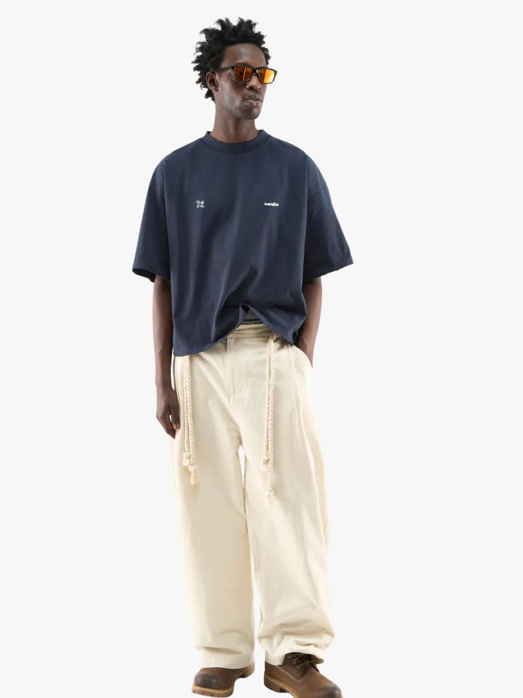 Man wearing a navy blue t-shirt and beige pants on a white background