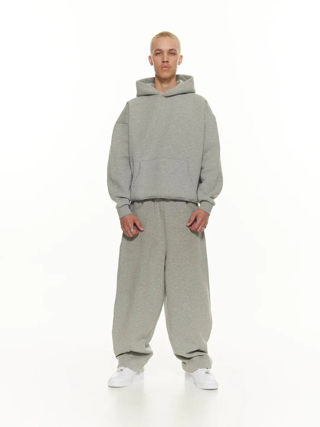 Person wearing a grey hoodie and pants set on a white background