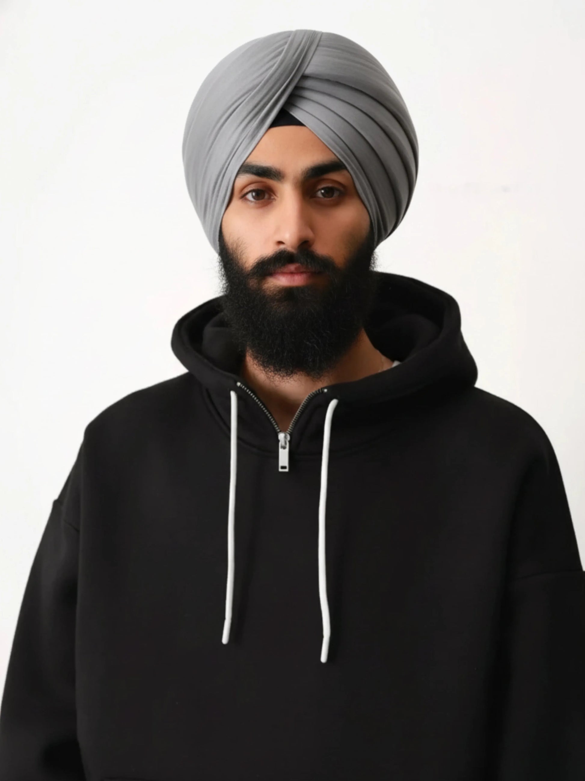 Man wearing a black hoodie and grey turban on a white background