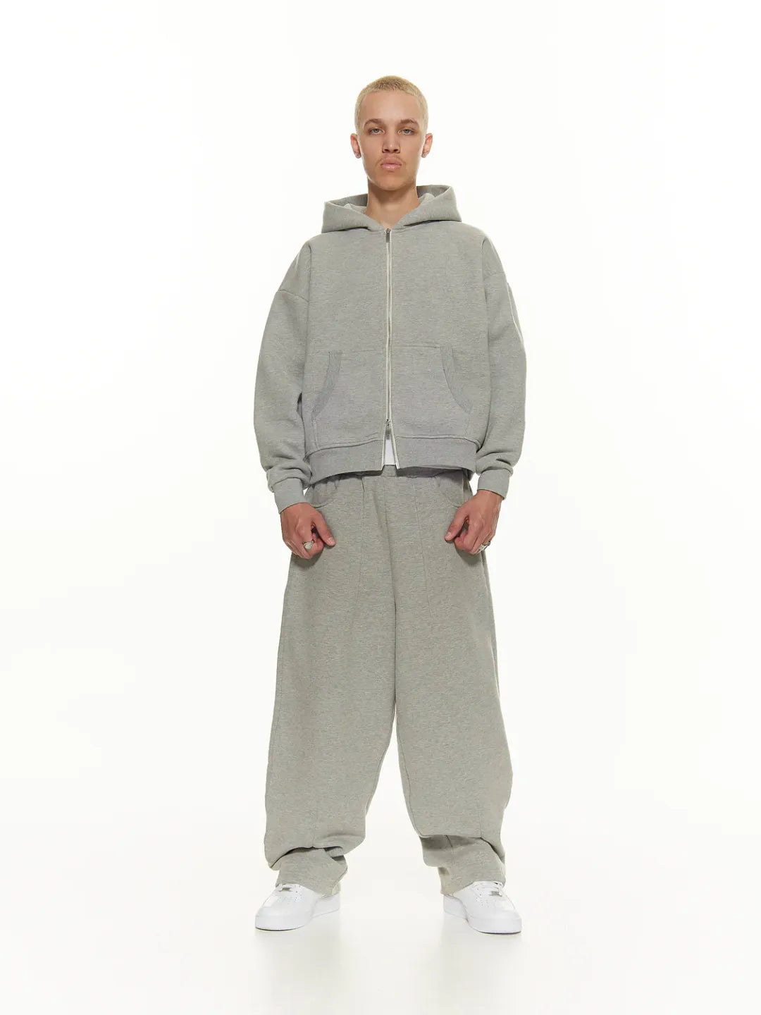 Person wearing a grey zip-up jacket on a white background