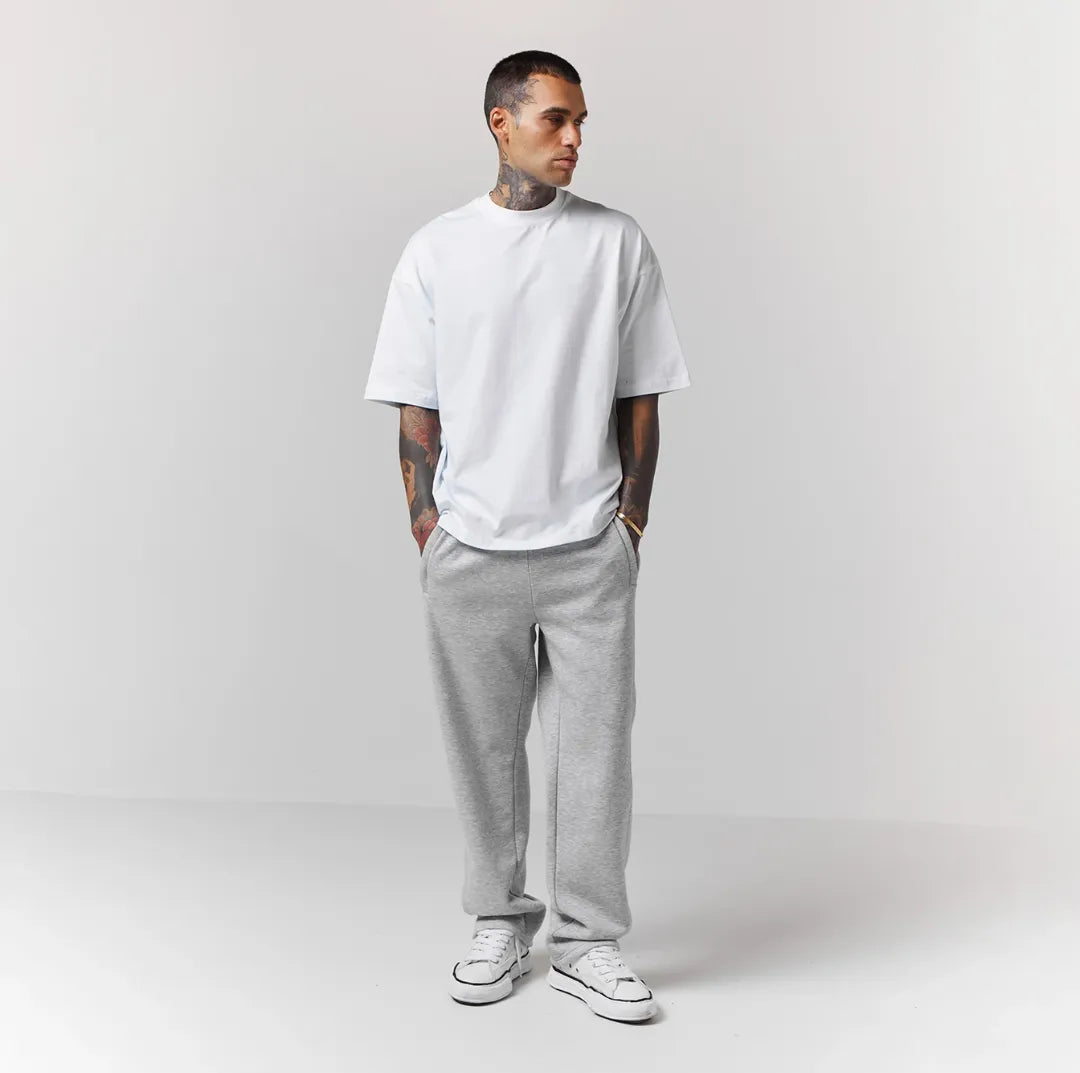 Person wearing a white t-shirt and grey jogger on a plain background