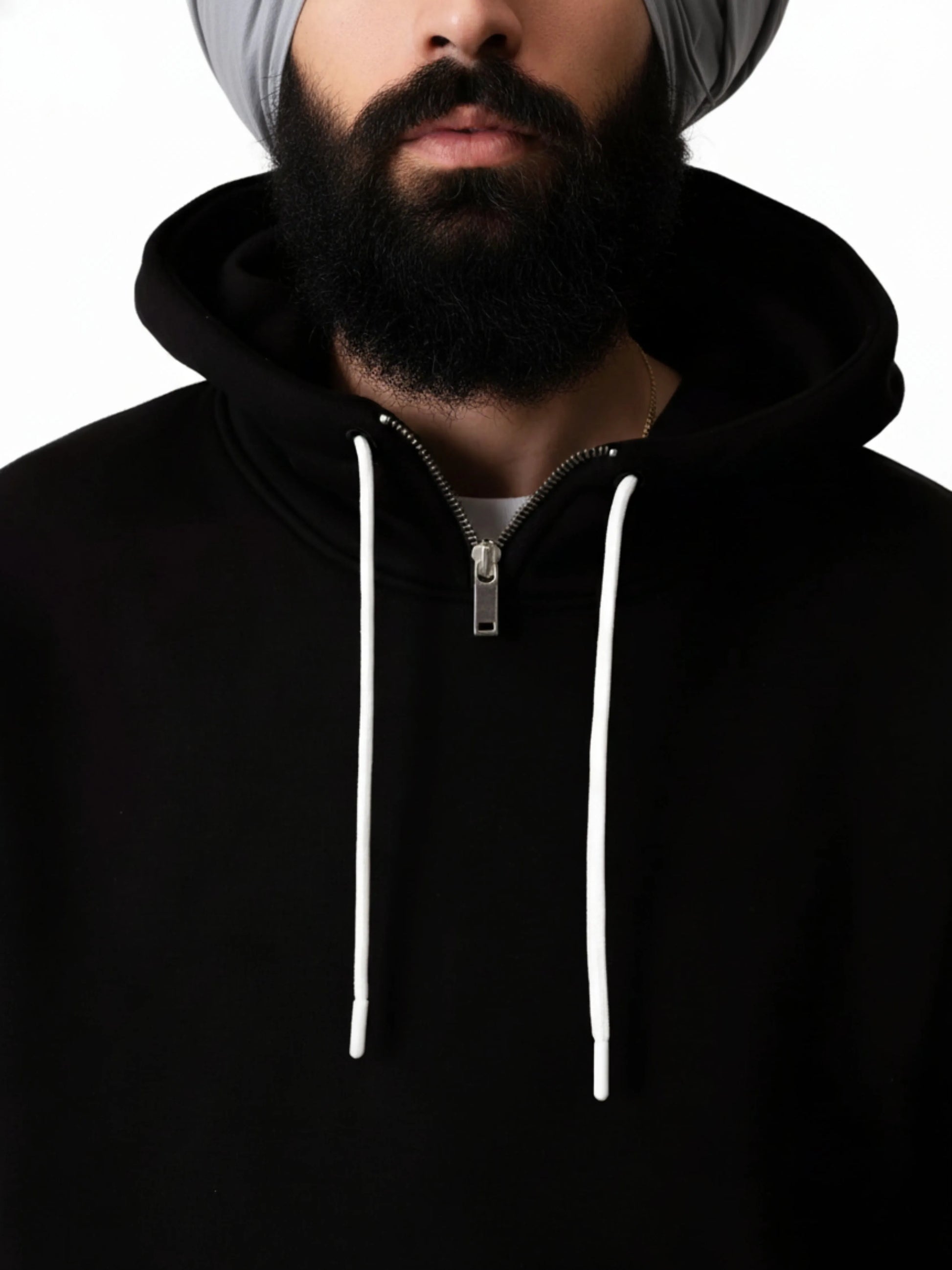 Person wearing a black hoodie with white drawstrings on a plain background