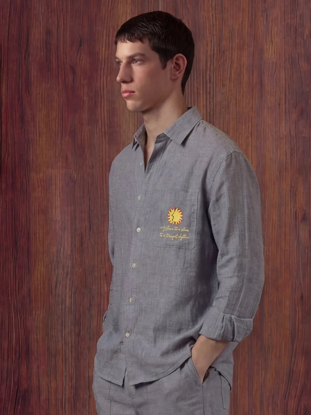 Man wearing a grey shirt with a sunflower design against a wooden background