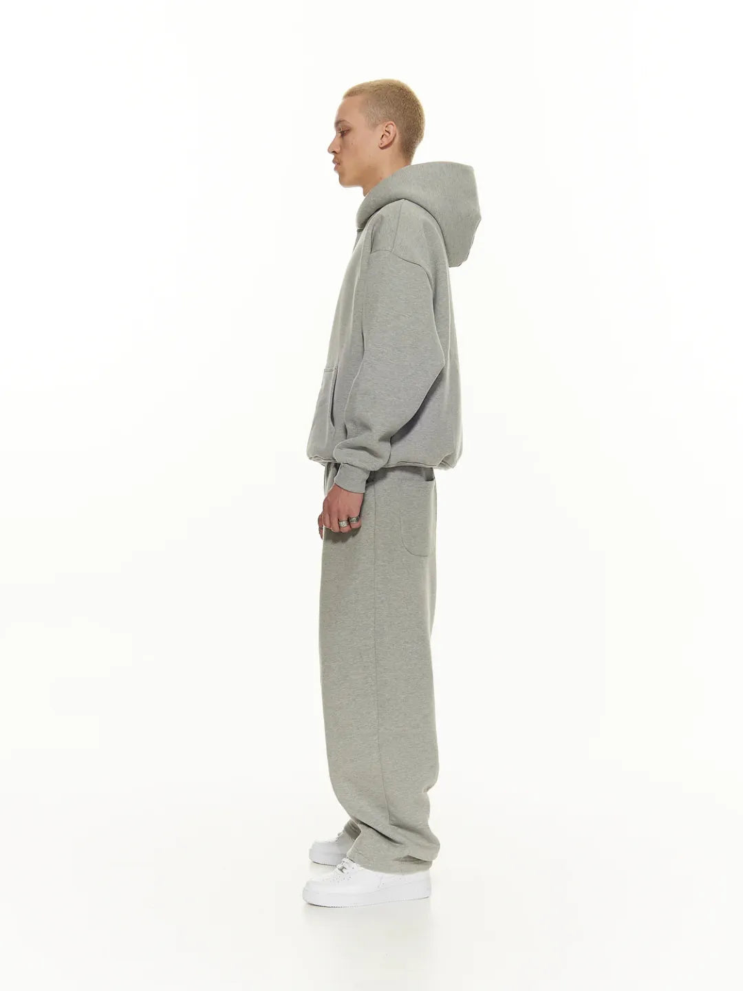 Person wearing a grey hoodie and pants on a white background