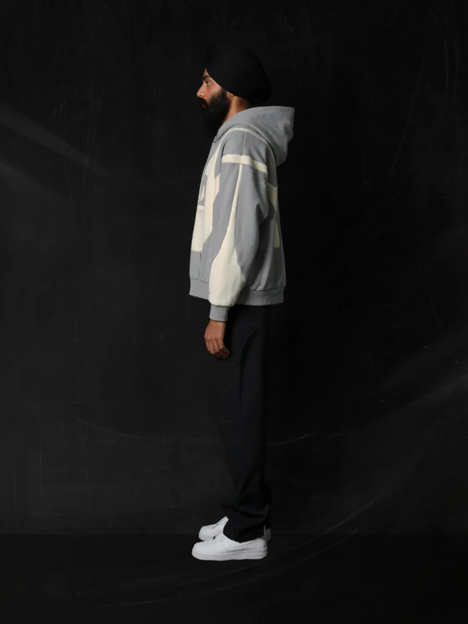 Person wearing a grey hoodie with geometric patterns on a black background