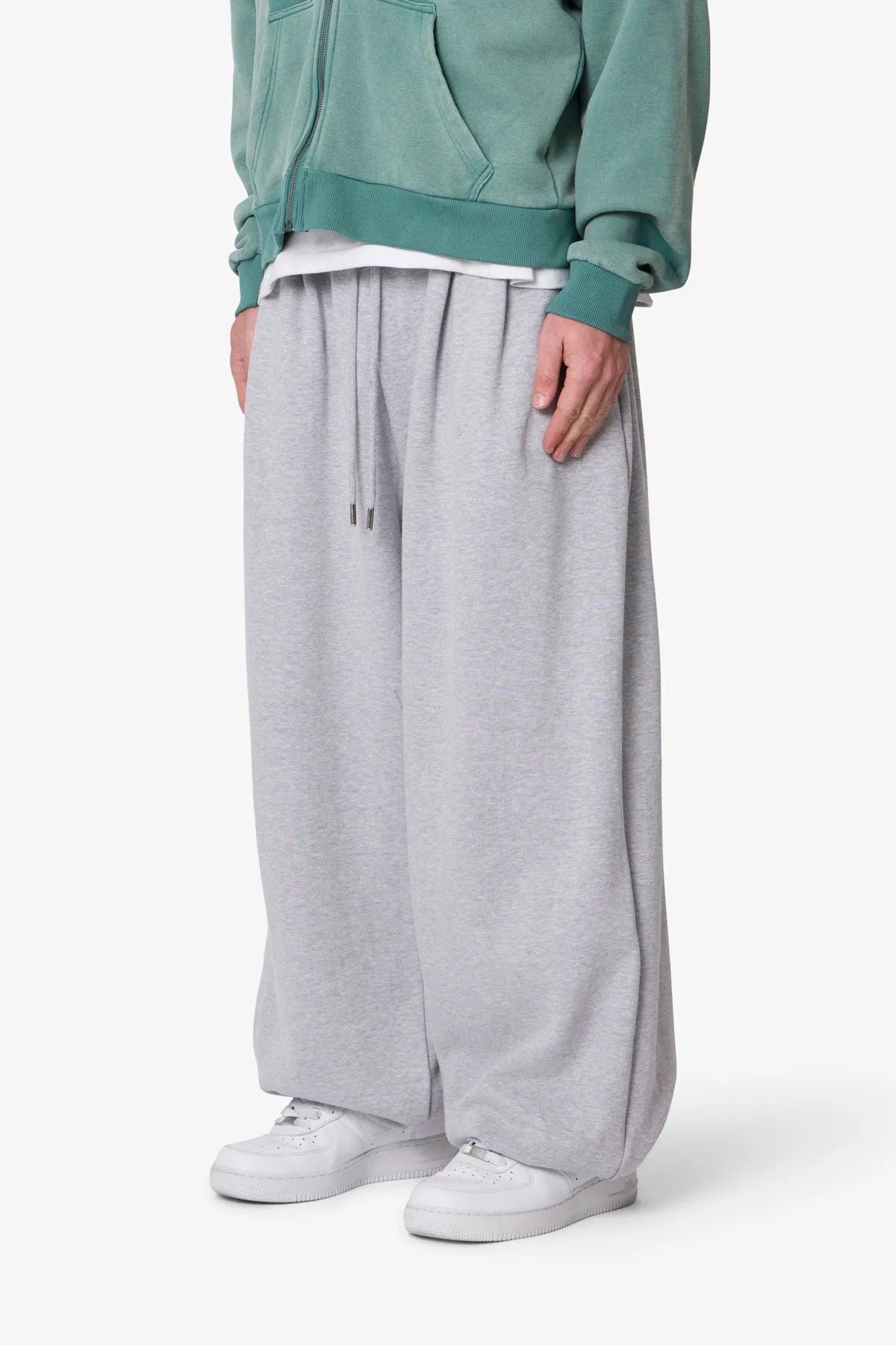 Person wearing grey baggy sweatpants with a plain background