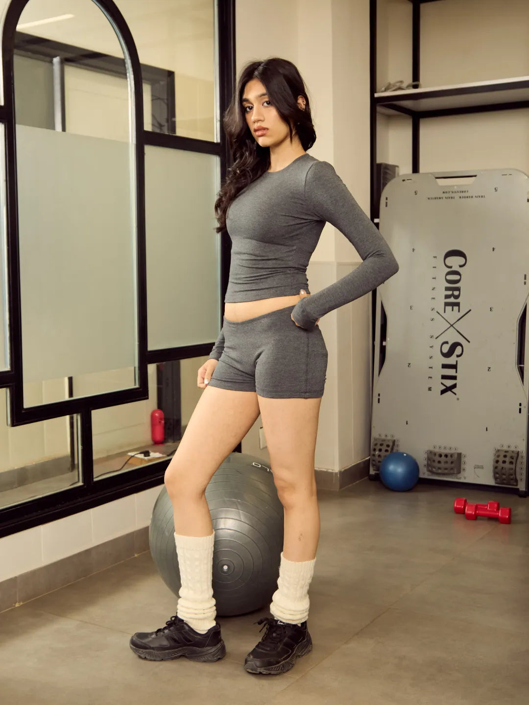 Woman in grey athletic wear posing in a gym setting
