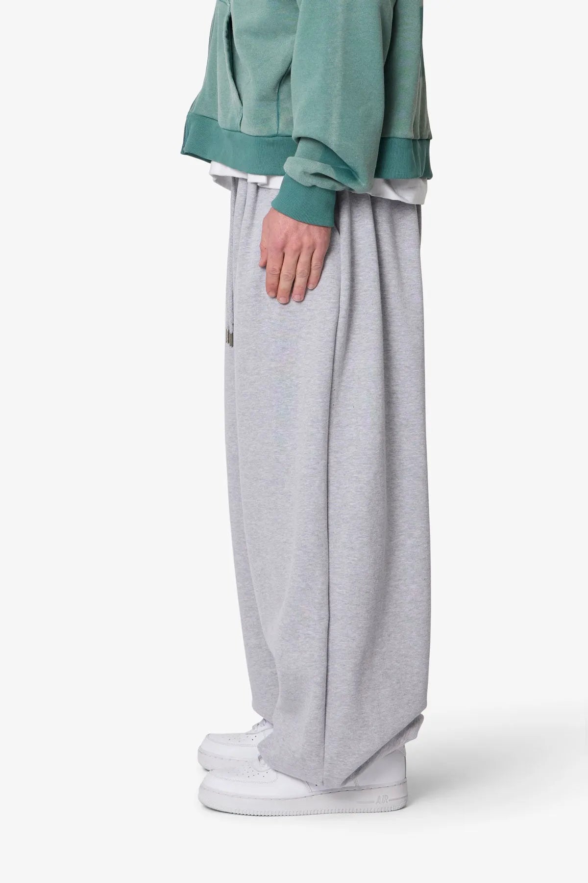 Person wearing grey baggy sweatpants with a plain background