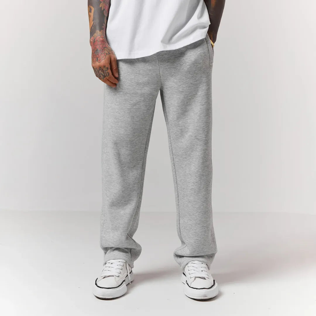 Person wearing grey jogger and white sneakers on a plain background