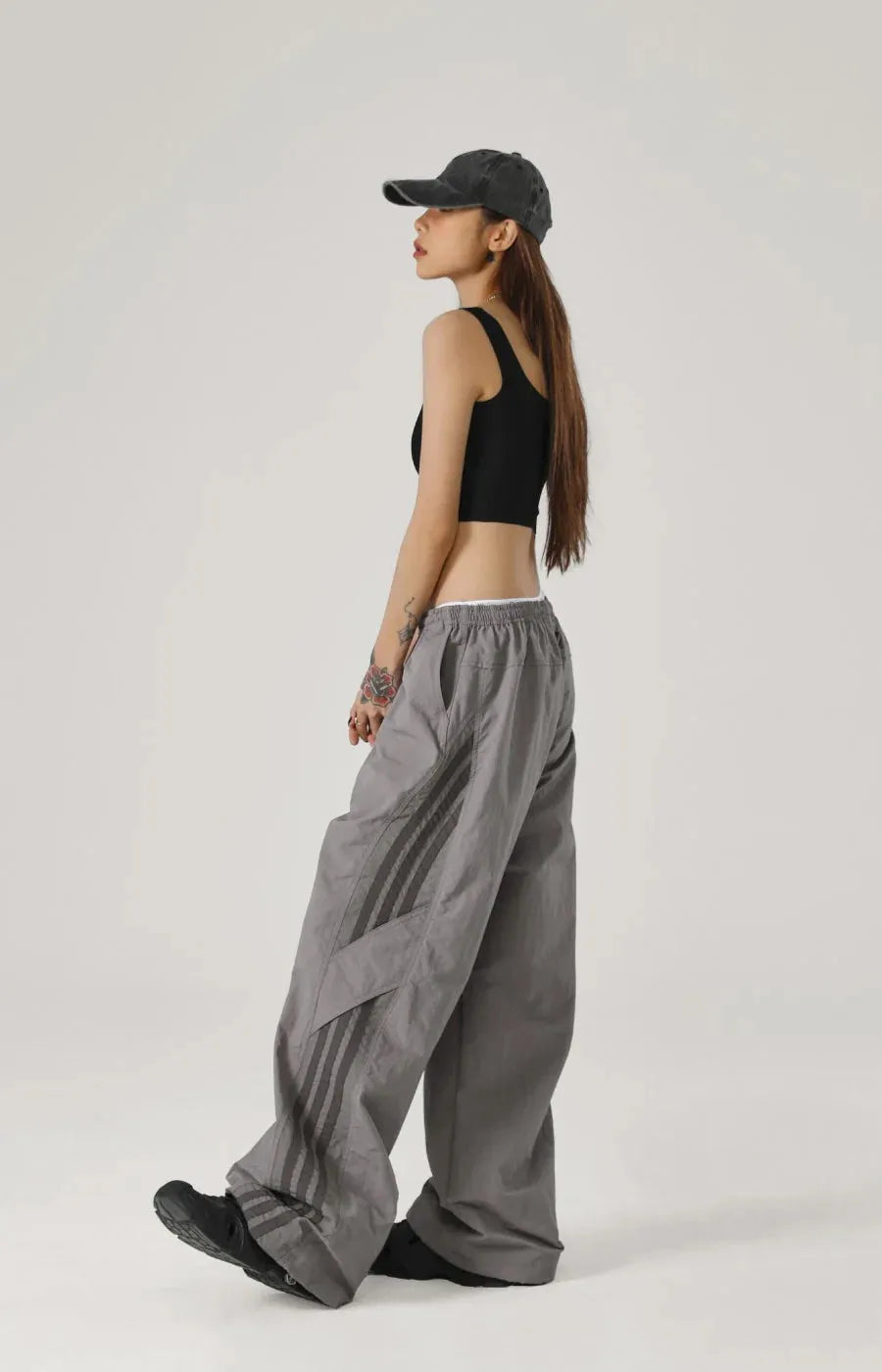 Person wearing a black crop top and grey wide-leg pants on a white background
