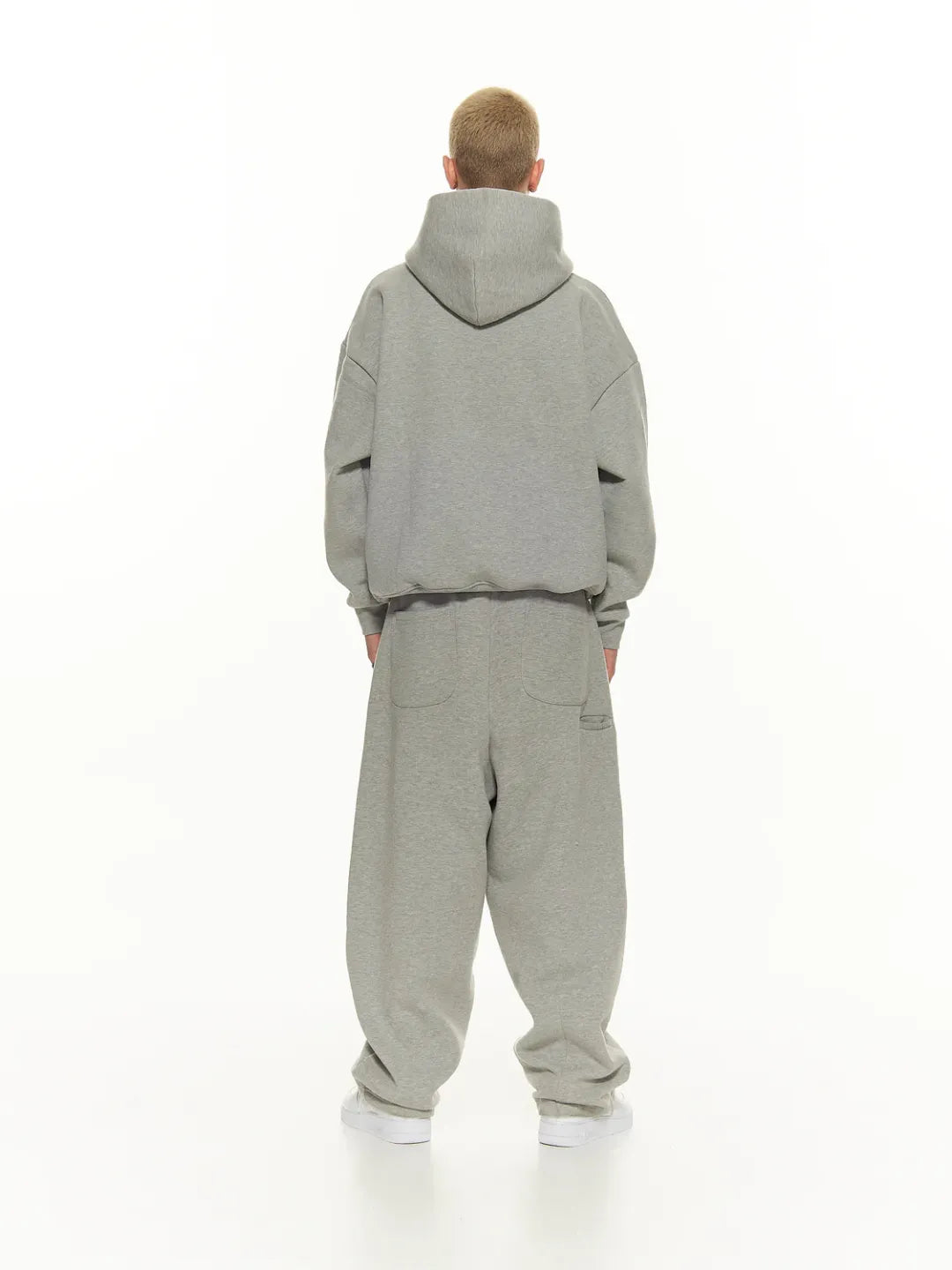 Person wearing a grey tracksuit on a white background