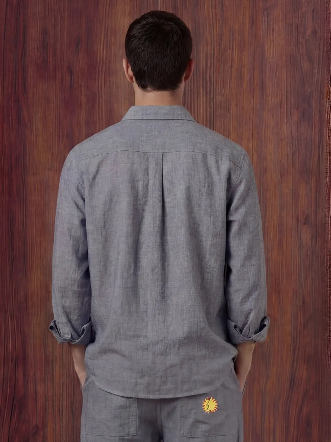 Person wearing a grey shirt with a sunflower emblem on a wooden background