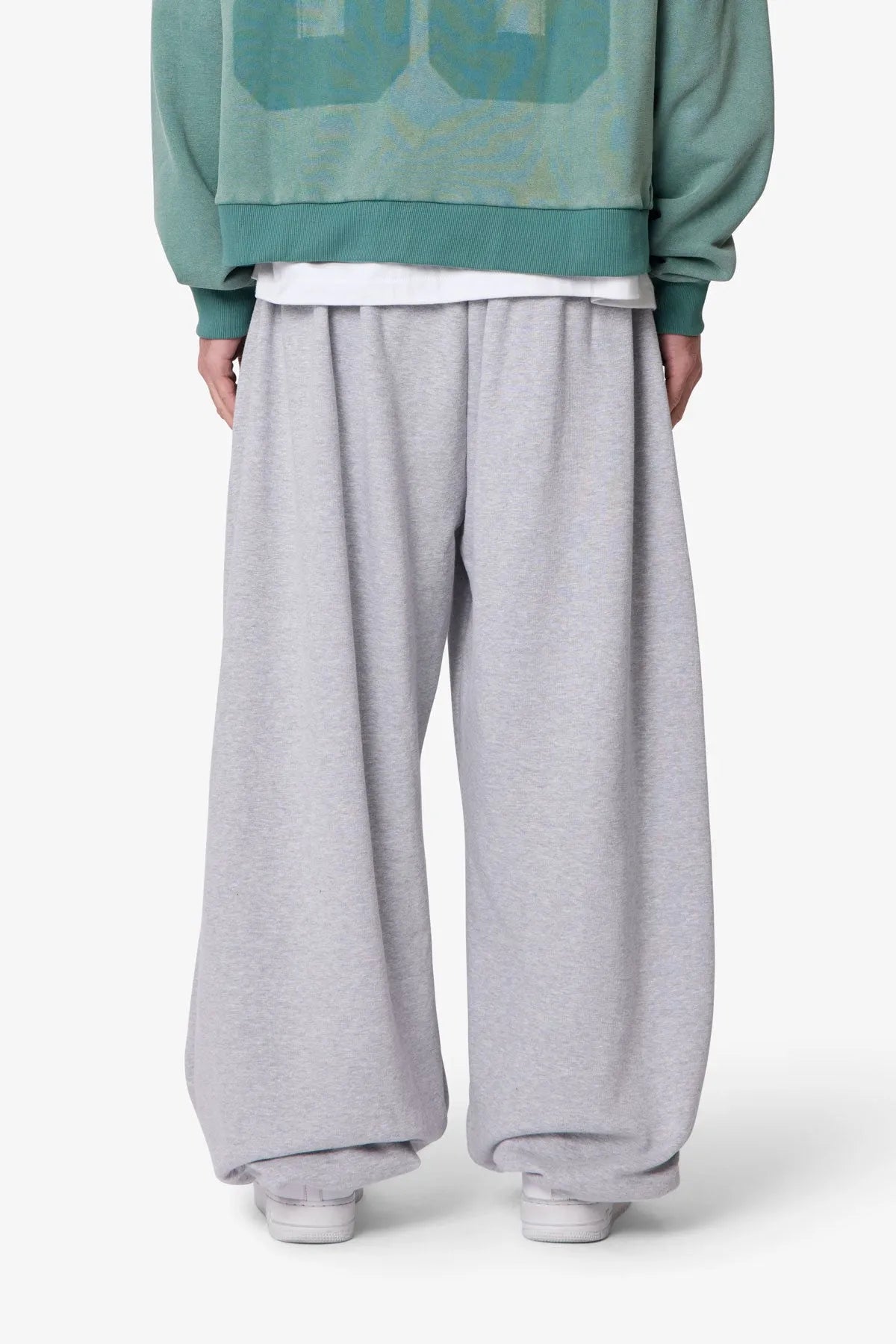 Person wearing grey baggy sweatpants with a plain background