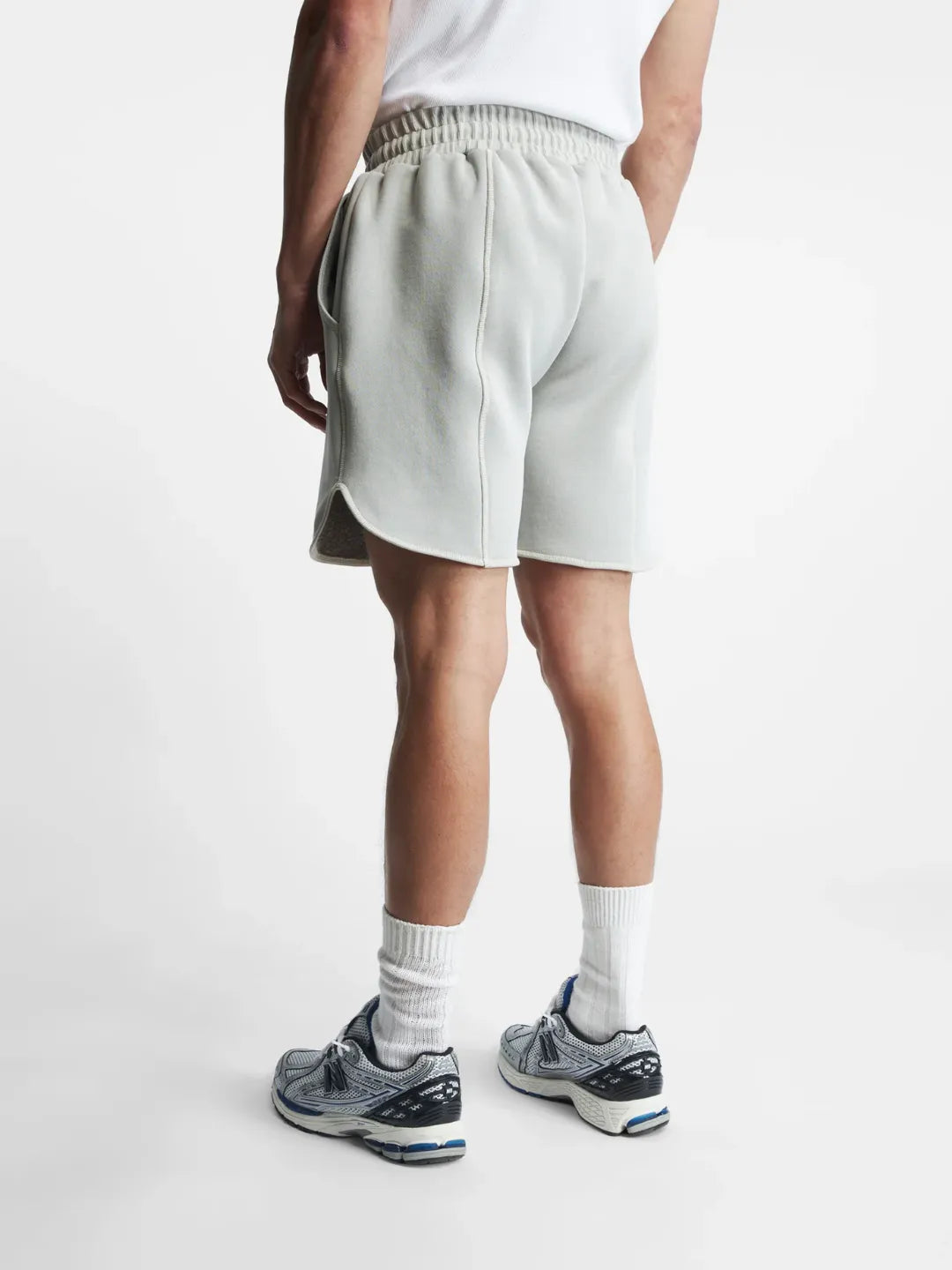 Person wearing light grey running shorts on a white background