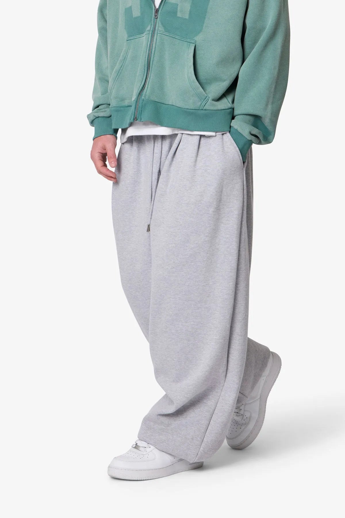 Person wearing grey baggy sweatpants with a plain background