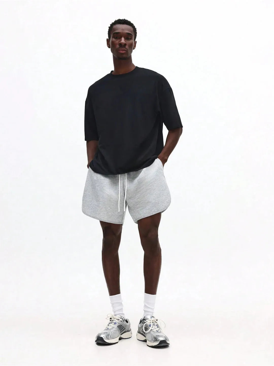 Man wearing a black shirt, white shorts, and white sneakers on a white background