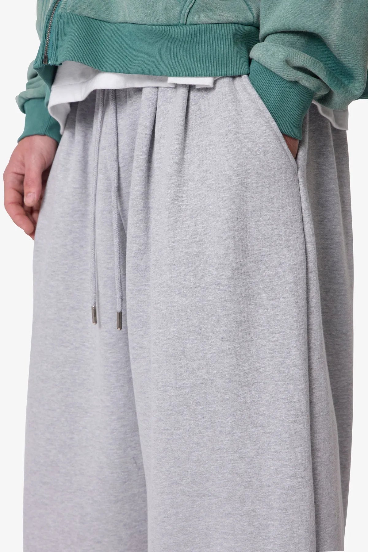Person wearing grey baggy sweatpants with a plain background