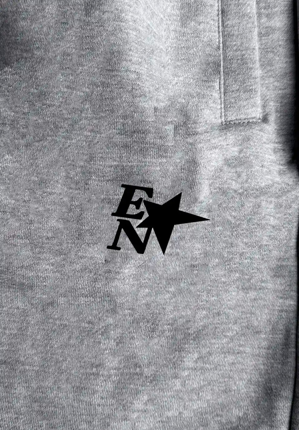 Close-up of a heather grey fabric surface with a black stylized 'EN' logo and star graphic printed at the center.
