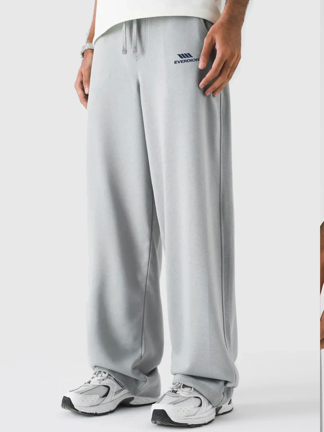 Person wearing grey pants with a brand logo on a white background