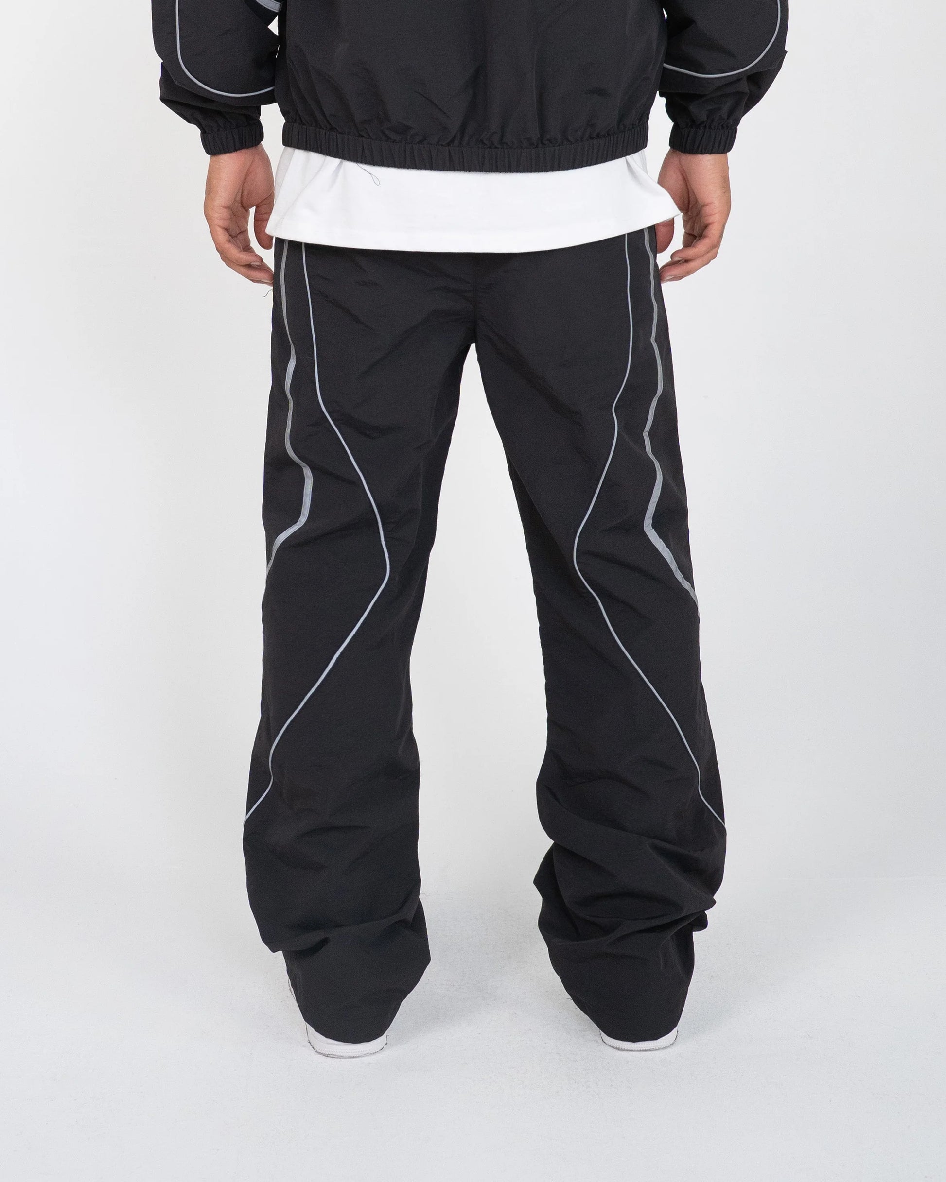 Person wearing black pants with white piping on a white background