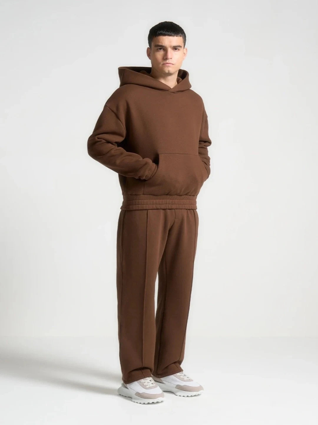 Man wearing a brown hoodie and pants set on a white background
