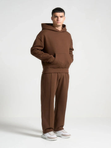 Man wearing a brown hoodie and pants set on a white background