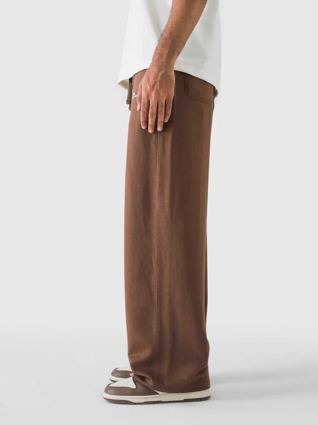 Brown pants worn by a person on a white background